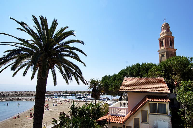Een prachtig uitzicht op de kerk, een palmboom en een zandstrand in San Lorenzo al Mare