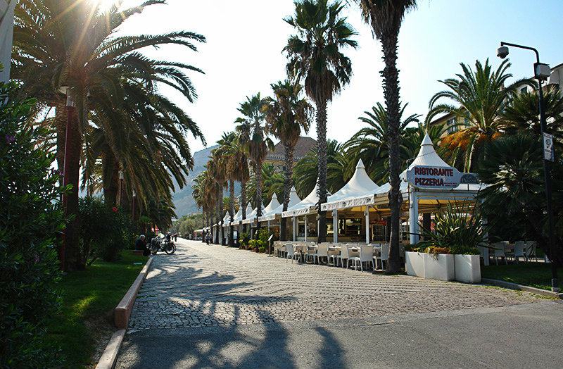 Een straat met palmbomen in Finale Ligure