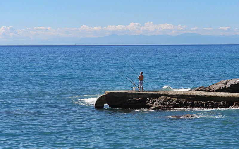 Een man is de visserij van stenen naast de zee in Recco