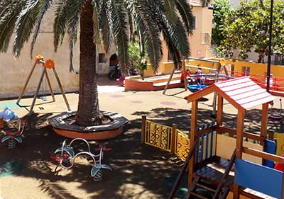 Een kleurrijke speeltuin voor kinderen onder een palmboom in Ligurië