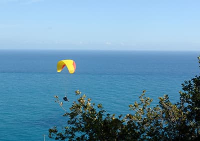 Een man paragliding over de zee in Ligurië